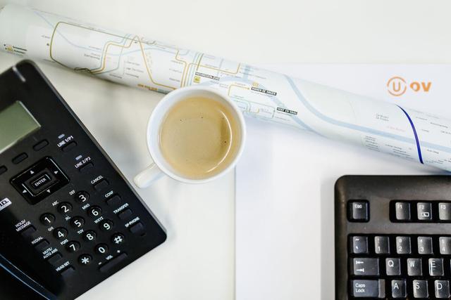 Een bureau op kantoor met toetsenbord, kopje koffie en U-OV briefpapier